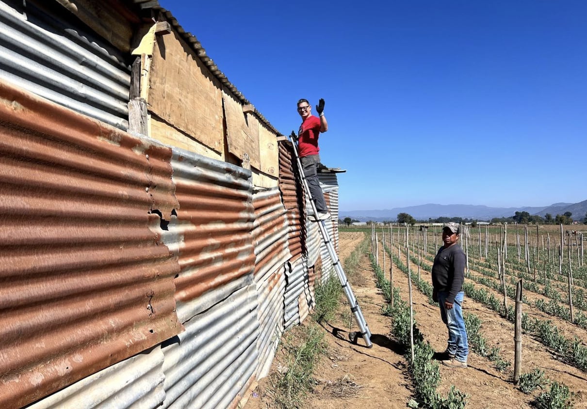 Volunteer fitting a stove pipe through a roof